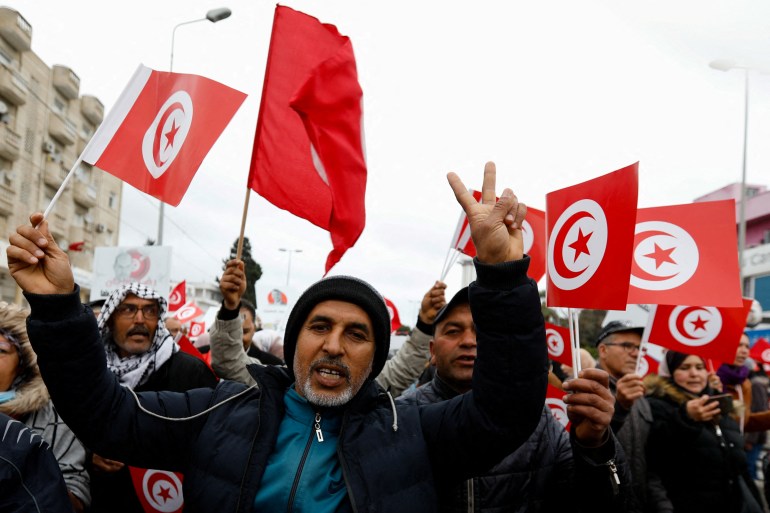 Demonstrators hold Tunisian national flags during a protest.