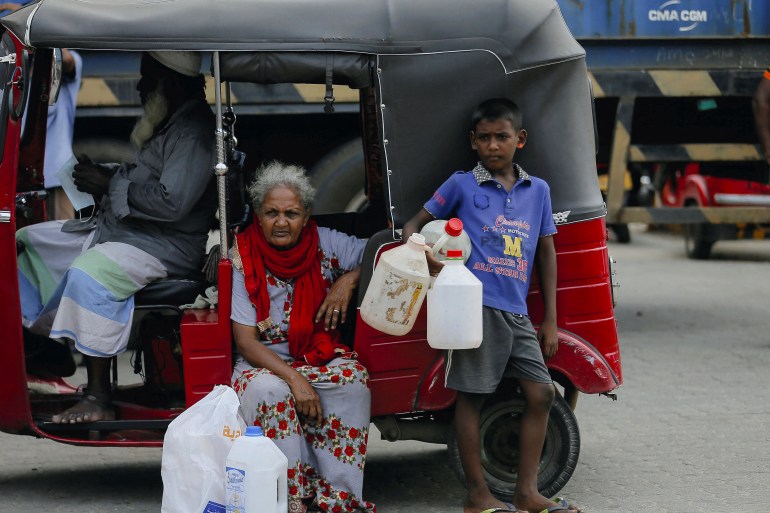 A boy holds empty containers as he waits with his family members to buy kerosene oil in Sri Lanka