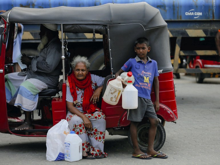 Un niño sostiene contenedores vacíos mientras espera con los miembros de su familia para comprar queroseno para cocinas de queroseno en medio de una escasez de gas doméstico en Sri Lanka