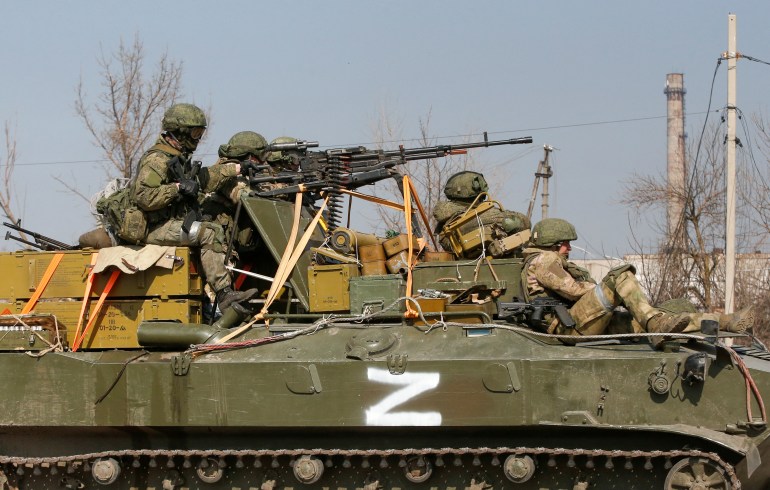 Service members of pro-Russian troops are seen atop of an armoured vehicle