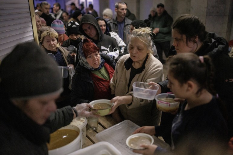 People who are sheltering in a metro station in northern Kharkiv receive food from volunteers