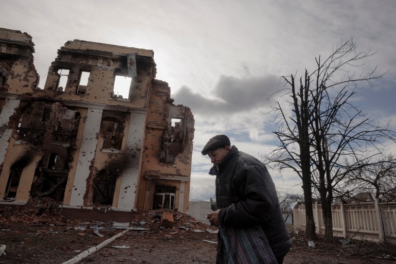 A man walks past a school that was damaged by fighting in Kharkiv