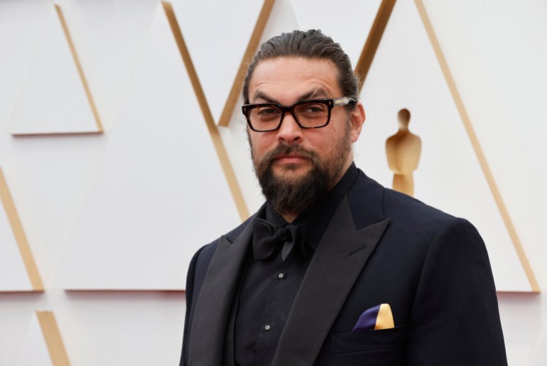 Jason Momoa wears a handkerchief in the colours of the Ukrainian flag in a show of solidarity for Ukraine as Russia's invasion of the country continues as he poses on the red carpet during the Oscars arrivals at the 94th Academy Awards in Hollywood, Los Angeles, 