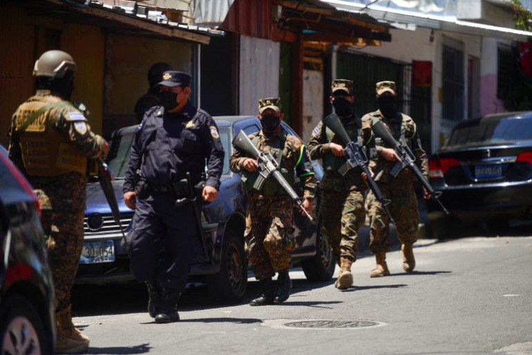 Bir polis memuru devriye sırasında askerlerin yanında yürüyor