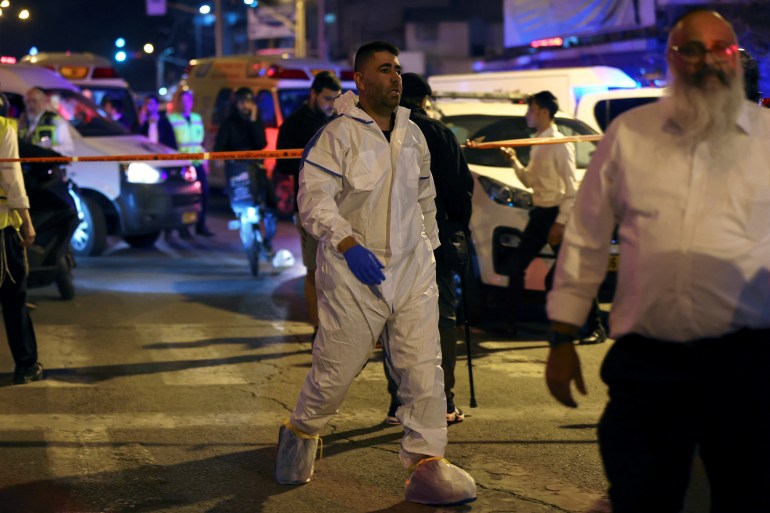 Israeli police forensics experts work at the scene of an attack in which people were killed by a gunman on a main street in Bnei Brak.