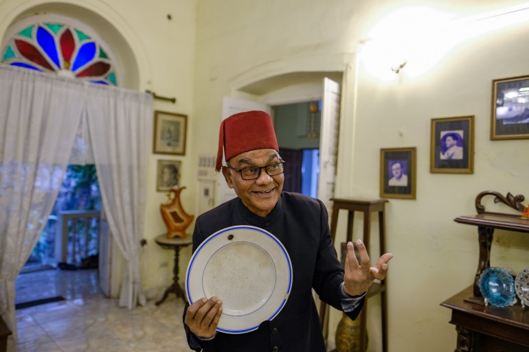 Emran stands holding an 100-year-old warming plate with a hole in the rim to fill it with hot water