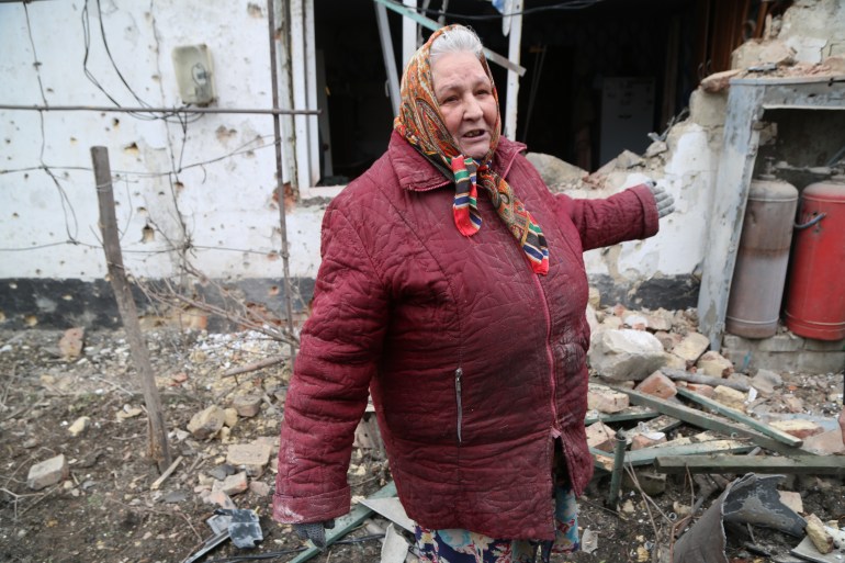 A woman is seen in front of a damaged building in Donetsk's Petrovskaya