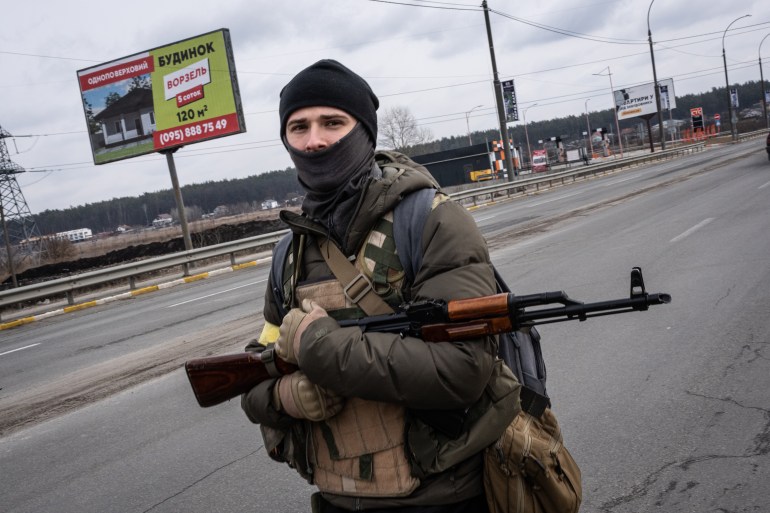 A photo of a Ukrainian soldier on the street holding a gun.