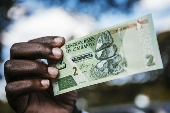 A man holds a 2 Zimbabwean two dollars bond banknote