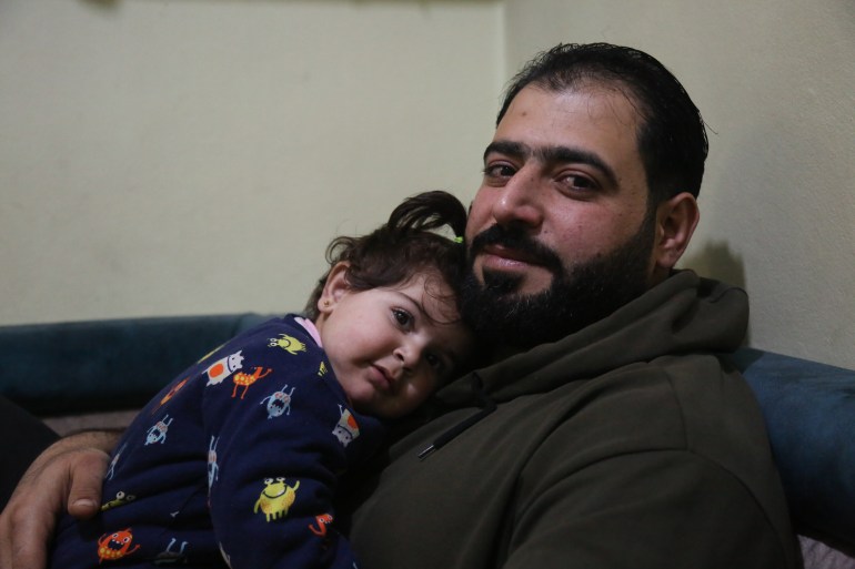 Amjad Al-Malah, holding his daughter, survived years of siege in Madaya with little food and medicine
