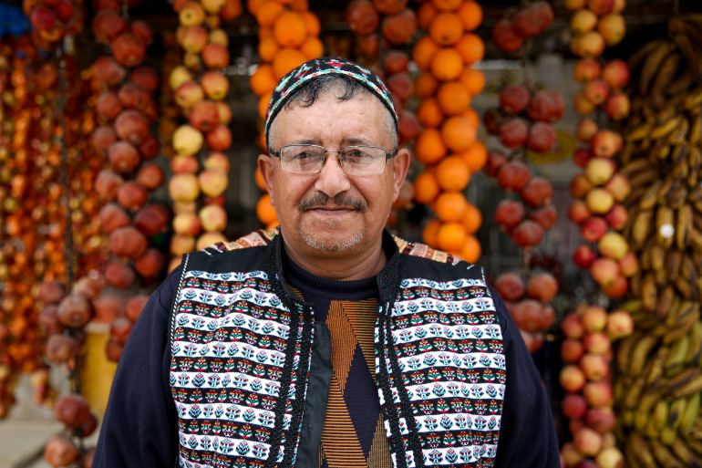 Safwan Daaboul stands in front of his shop, with strings of drying fruit behind him.