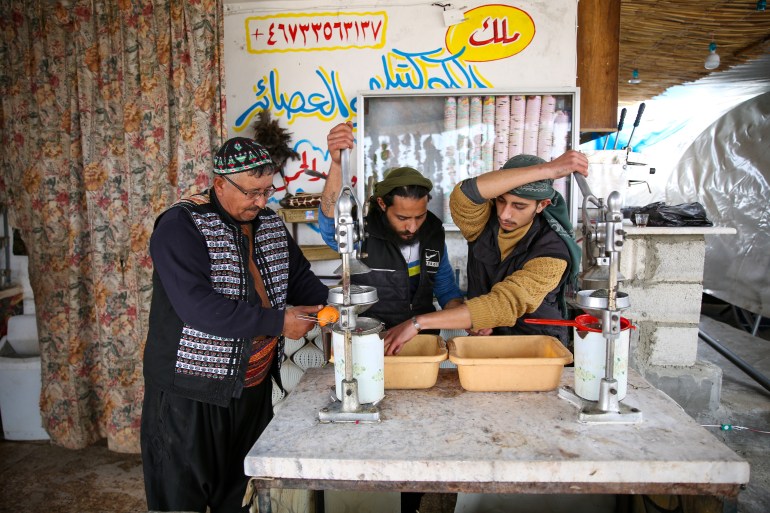 Safwan Daaboul and two workers juice oranges using two traditional metal juice presses.