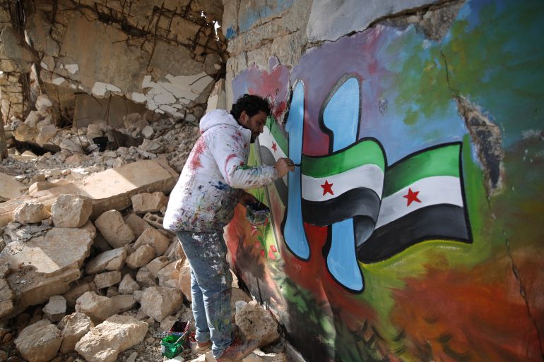 Syrian artist Aziz al-Asmar paints murals and banners in the northwestern city of Binnish ahead of protests to commemorate the 11th anniversary of the Syrian uprising.