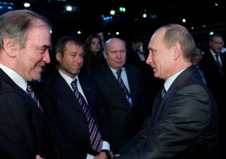 Russian Prime Minister Vladimir Putin, right, congratulates members of the Russian delegation
