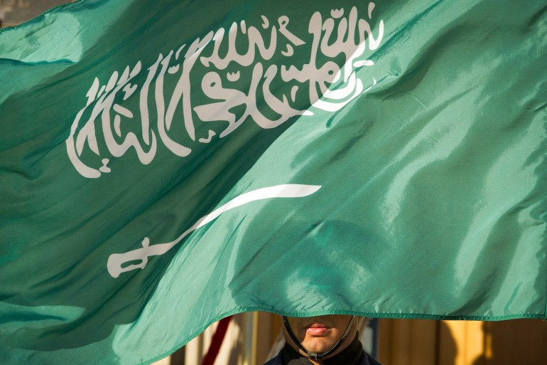 An honor guard member is covered by the flag of Saudi Arabia, in Washington