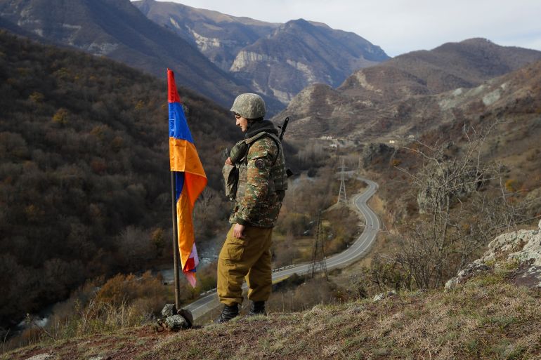An Armenian soldier next to a Nagorno-Karabakh flag