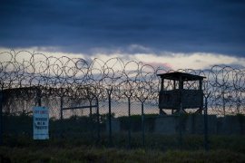 The sun sets behind barbed wire and a guard tower at the wartime Camp X-Ray detention facility in Guantanamo Bay Naval Base, Cuba.