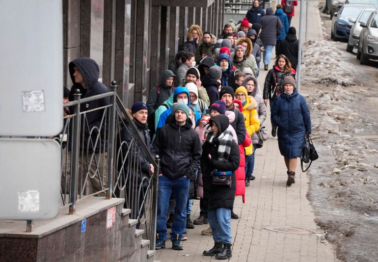 People stand in line to withdraw US dollars and Euros from an ATM in St.  Petersburg, Russia, Friday, Feb.  25, 2022. Ordinary Russians faced the prospect of higher prices and crimped foreign travel as Western