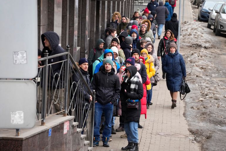 People stand in line to withdraw U.S. dollars and Euros from an ATM in St. Petersburg, Russia, Friday, Feb. 25, 2022. Ordinary Russians faced the prospect of higher prices and crimped foreign travel as Western
