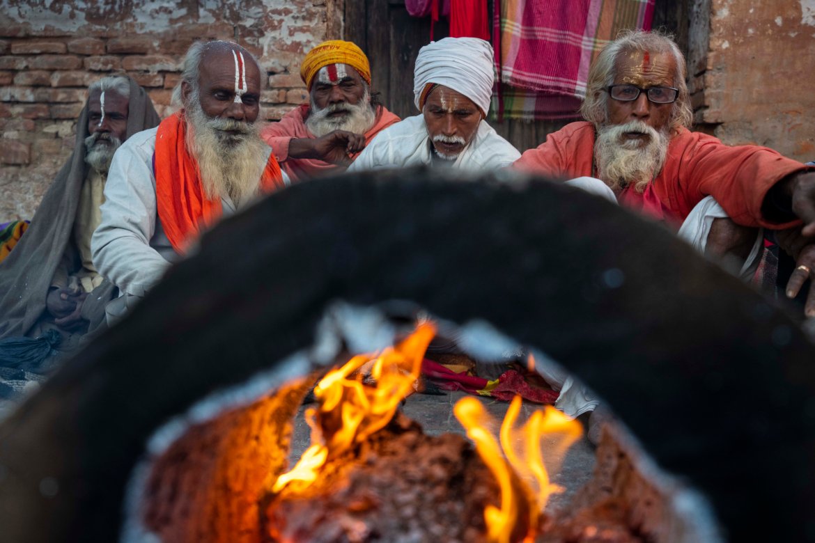Holy men from India warm themselves sitting next to a bonfire