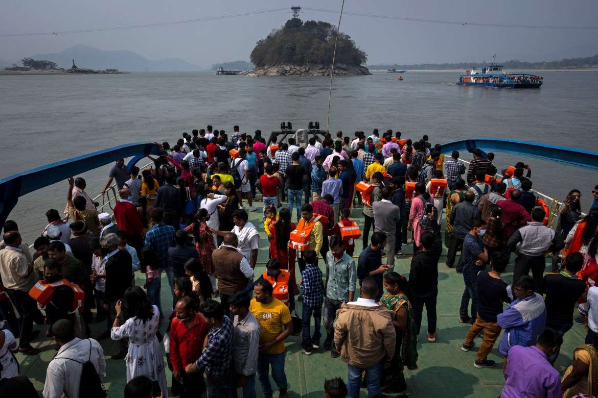 Devotees travel on a ferry to Umananda ,behind, a river island in the Brahmaputra that houses a temple of Hindu god Shiva, during Shivratri festival, in Gauhati, India,