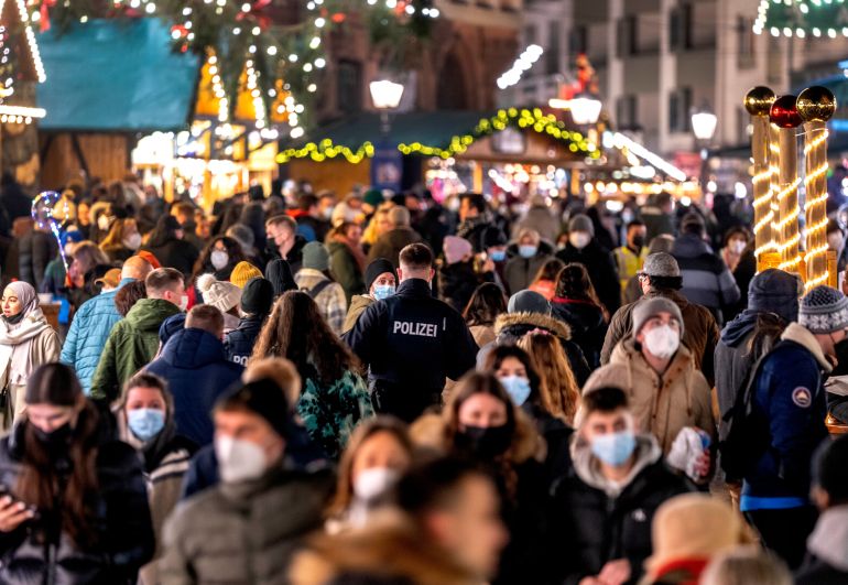 FILE - Crowds of masked people visit the Christmas market on its final day in Frankfurt, Germany, Wednesday, Dec. 22, 2021. The official global death toll from COVID-19 is on the verge of eclipsing 6 million — underscoring that the pandemic, now in its third year, is far from over.