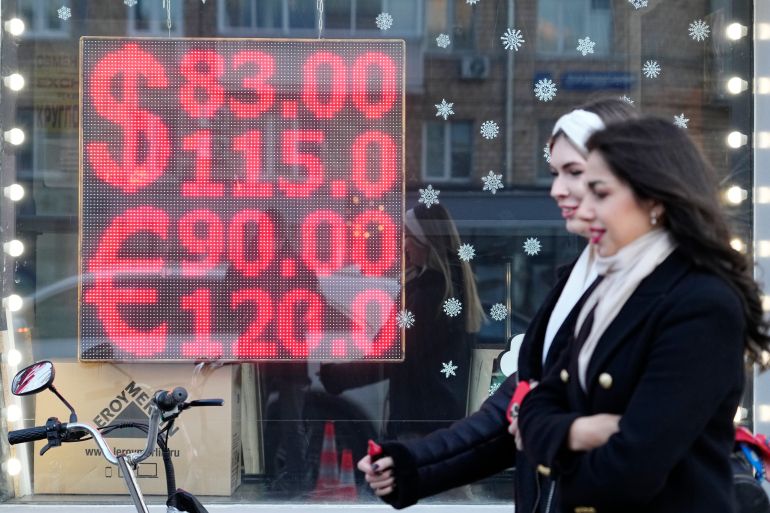 People walk past a currency exchange office screen displaying the exchange rates of U.S. Dollar and Euro to Russian Rubles in Moscow's downtown
