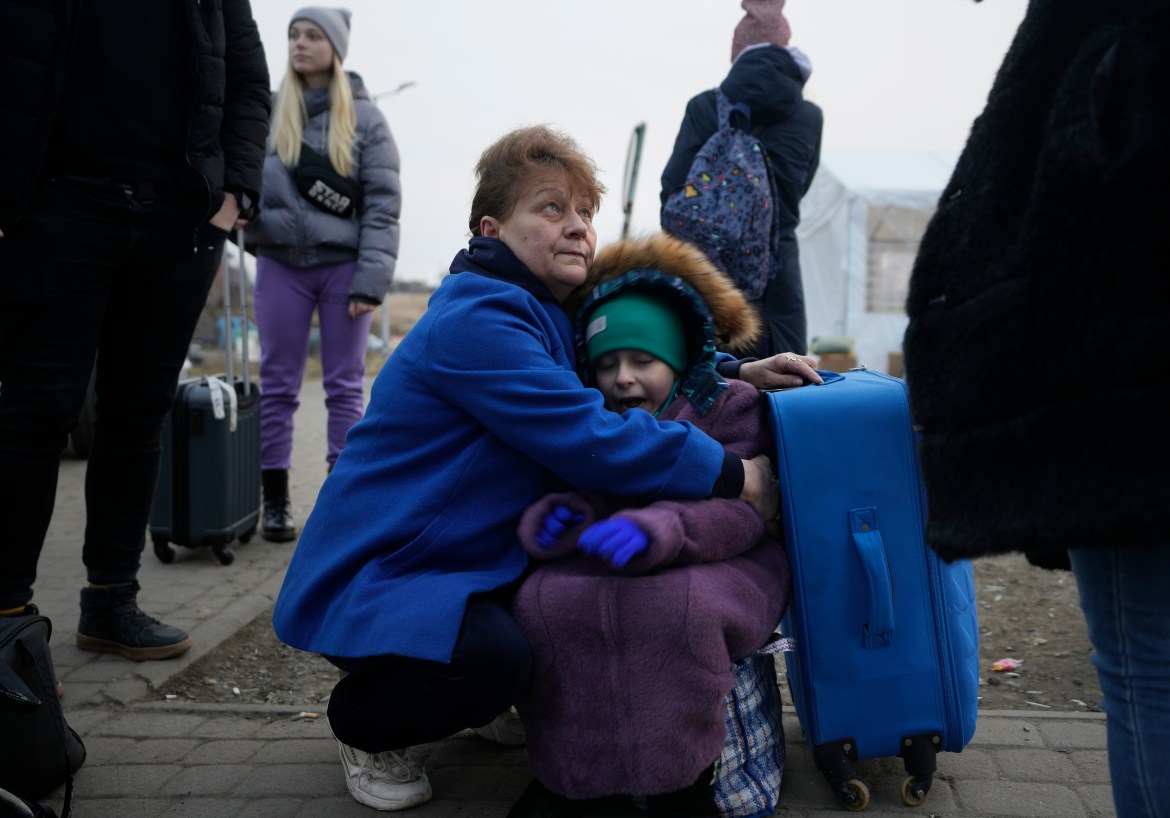 A woman holds a small girl at a border crossing, up as refugees flee a Russian invasion, in Medyka, Poland,