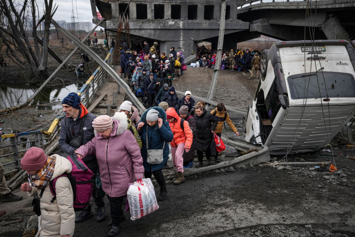 People cross on an improvised path under a bridge that was destroyed by a Russian air raid while fleeing the town of Irpin
