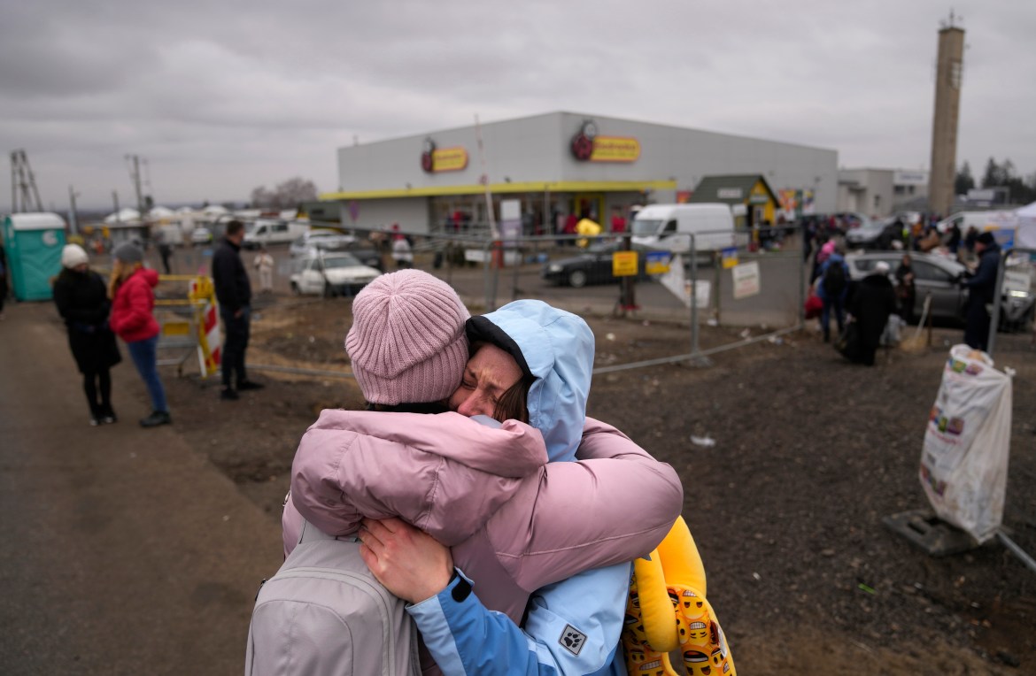 A woman weeps after finding a friend, who also fled Ukraine, at the border crossing in Medyka