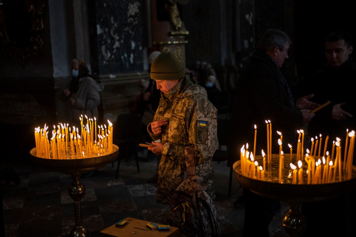 A Ukrainian woman dressed in military attire prays inside the Saints Peter and Paul Garrison Church in Lviv