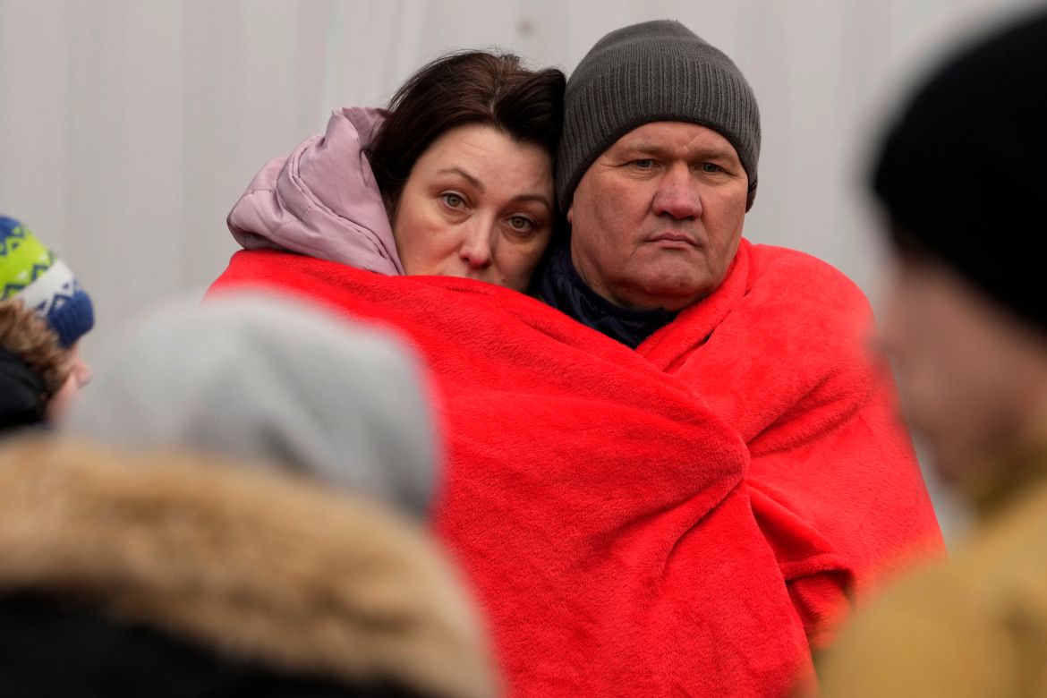 Refugees that fled Ukraine from the war cover themselves with a blanket while they wait for a bus to leave Korczowa border crossing, Poland