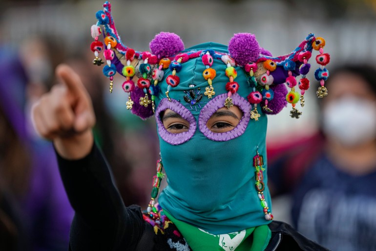 A costumed demonstrators performs the song "Un violador en tu camino" or A rapist in your path