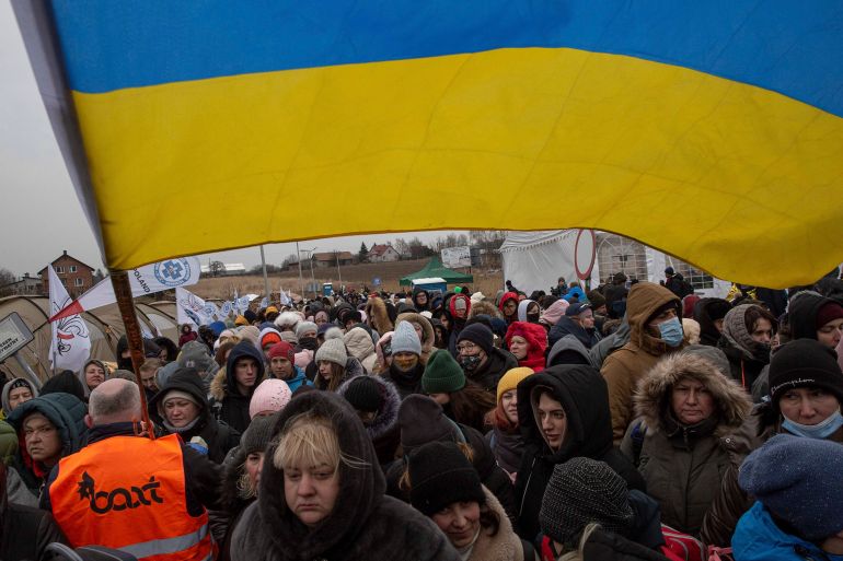 A Ukrainian volunteer Oleksandr Osetynskyi, 44 holds a Ukrainian flag and directs refugees after fleeing from Ukraine and arriving at the border crossing in Medyka, Poland