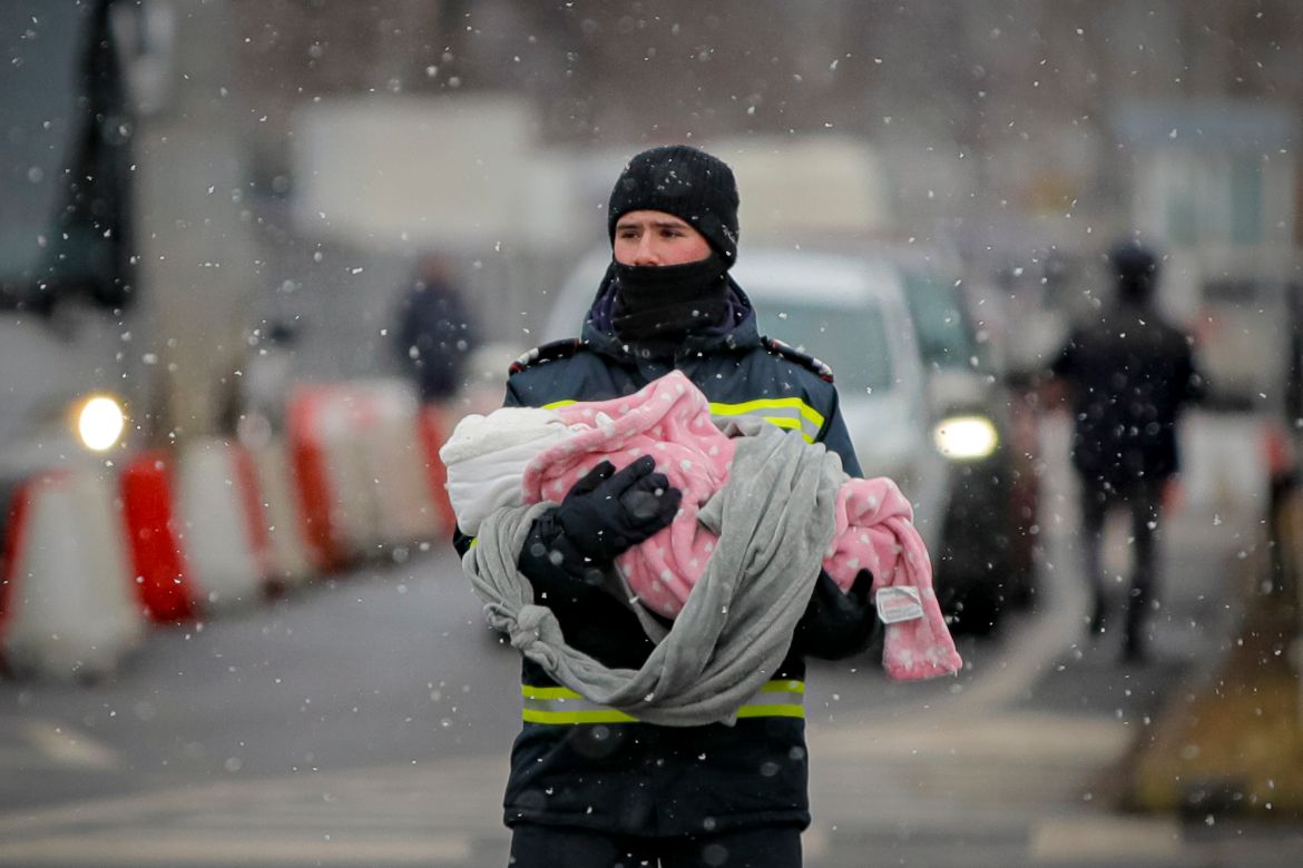 A firefighter holds the baby of a refugee fleeing the conflict from neighboring Ukraine at the Romanian-Ukrainian border