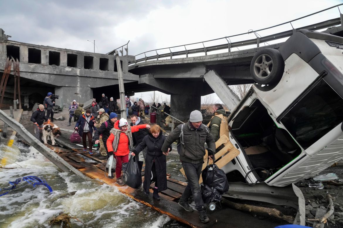 People cross an improvised path under a destroyed bridge while fleeing the town of Irpin close to Kyiv
