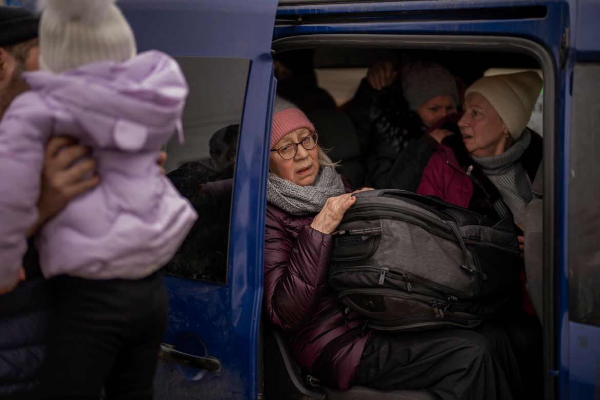 Ukrainian women sit inside a van as artillery echoes nearby, as people flee Irpin on the outskirts of Kyiv