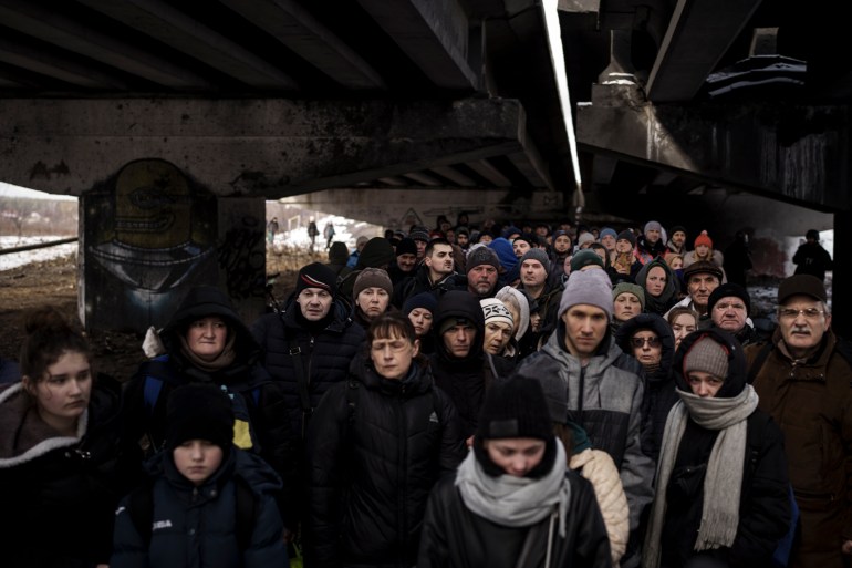 Ukrainians are seen crowding under a destroyed bridge as they try to flee crossing the Irpin river