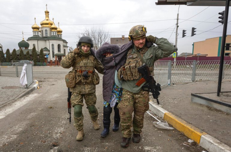 Ukrainian servicemen help evacuate an elderly woman, in the town of Irpin, Ukraine on March 6, 2022..