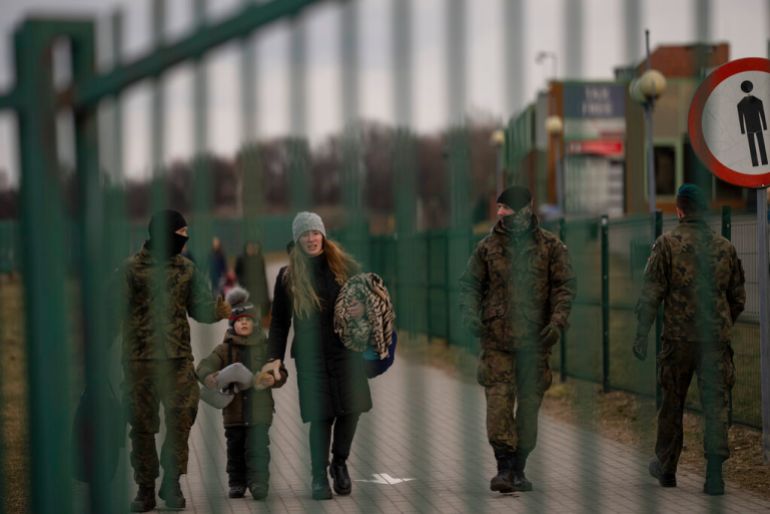 A soldier carries a bag as he is helps a woman and a children fleeing from Ukraine, on their arrival at the border crossing in Medyka, Poland.