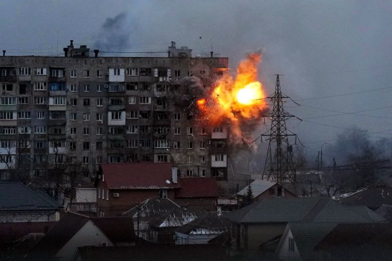 An explosion is seen in an apartment building after a Russian army tank fires in Mariupol, Ukraine