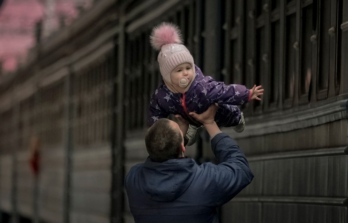 A man plays with a child before she boards a Lviv bound train, in Kyiv