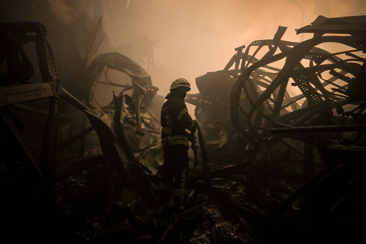 A Ukrainian firefighter drags a hose inside a large food products storage facility which was destroyed by an airstrike