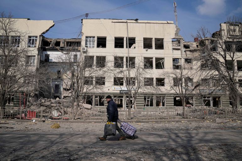 A man walks past a building damaged by shelling in Mira Avenue (Avenue of Peace) in Mariupol, Ukraine