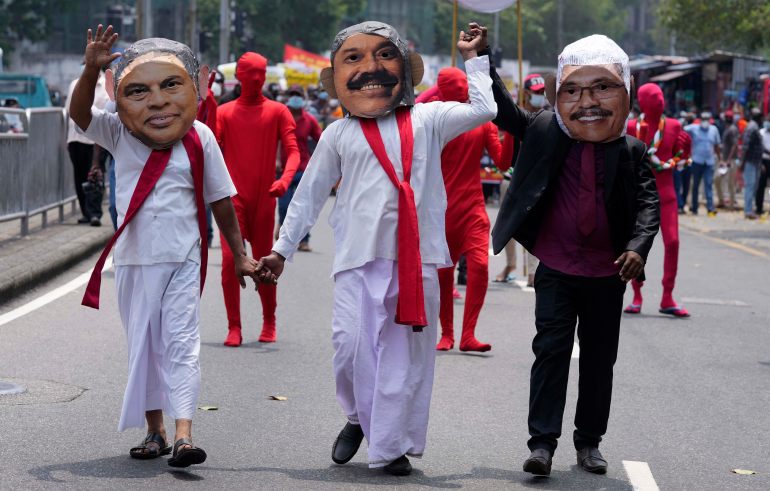 Sri Lankan protesters dressed as President Gotabaya Rajapaksa and his brothers walk on a street of Colombo, Sri Lanka.
