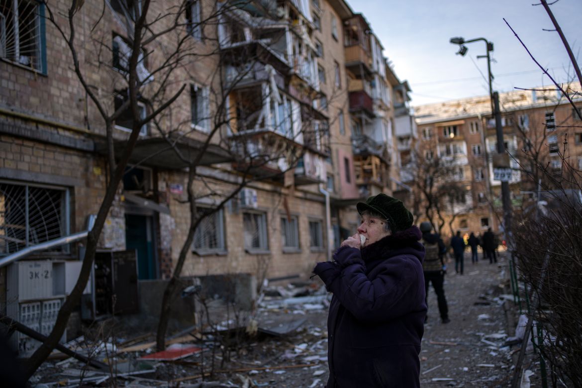 A woman looks at residential buildings damaged by a bomb in Kyiv
