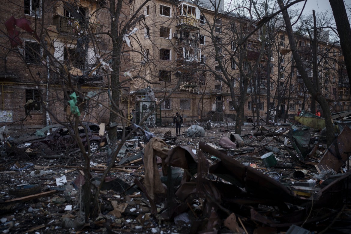 A constabulary  serviceman  walks astatine  the tract  of a bombing that damaged residential buildings successful  Kyiv