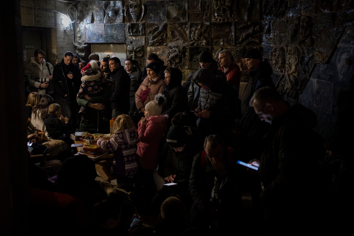 People gather in a basement, used as a bomb shelter, during an air raid in Lviv