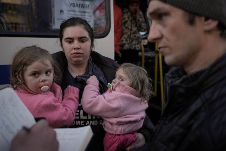 Refugiados esperan a que la policía ucraniana revise sus papeles y pertenencias en Brovary, Ucrania