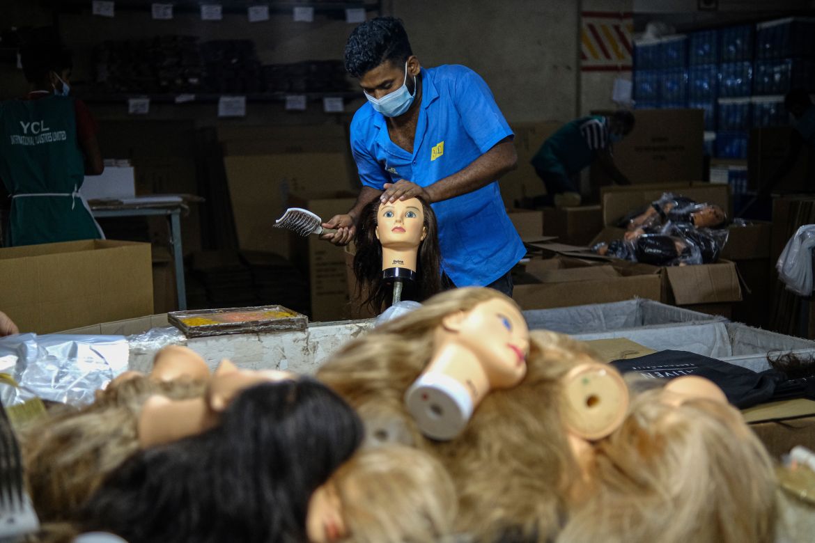 A worker brushes mannequin wigs at a factory inside an export processing zone in Mongla